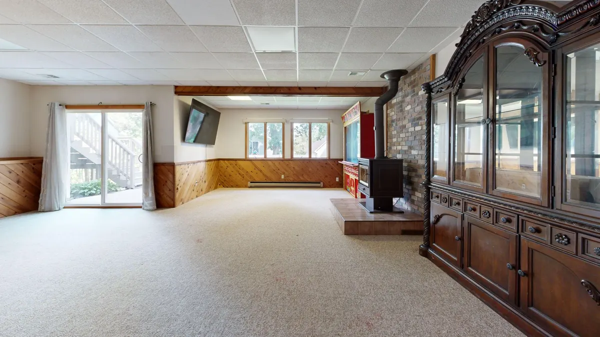 Finished cozy basement lounge with wood paneling and a fireplace